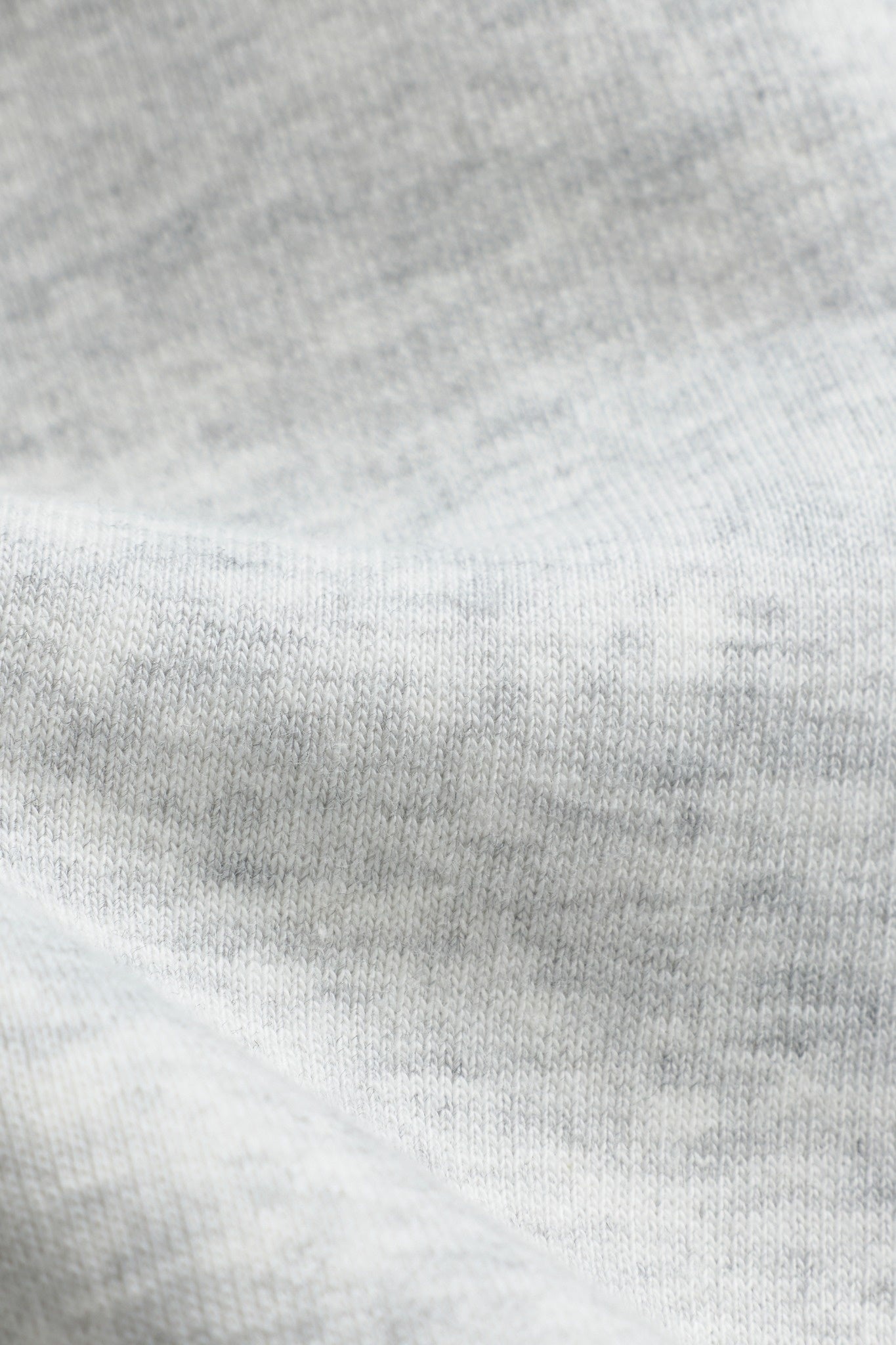 Close-up of soft grey melange cotton fabric texture on a CASPARA crewneck sweatshirt.